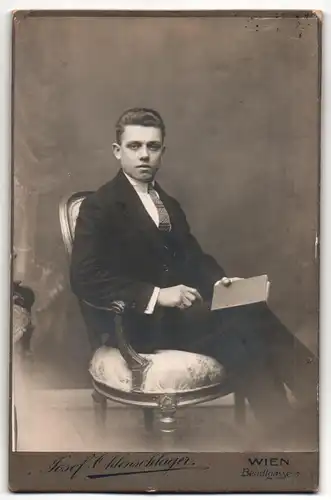 Fotografie Josef Ohlenschlager, Wien, Portrait sitzender Herr im Anzug mit Krawatte und Buch