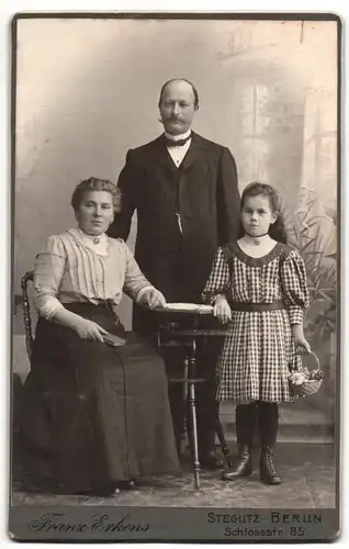 Fotografie Franz Erkens, Berlin-Steglitz, Portrait bürgerliches Paar mit einer kleinen Tochter am Tisch