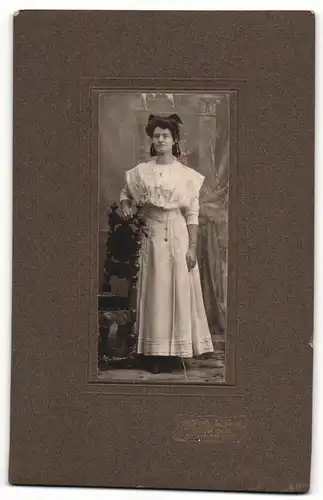 Fotografie Alb. Grünbeck, Sonneberg, Portrait junge Dame im weissen Kleid an Stuhl gelehnt