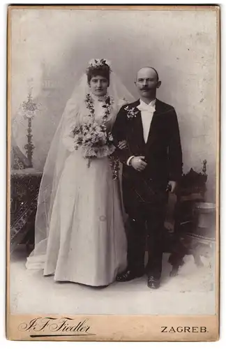 Fotografie J. F. Fiedler, Zagreb, kroatisches Brautpaar im Hochzeitskleid und Anzug mit Brautstrauss und Zylinder