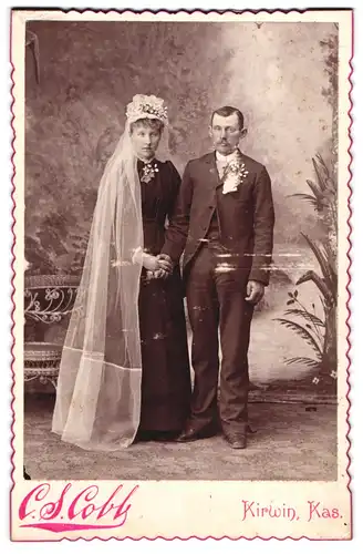 Fotografie C. S. Cobb, Kirwin / Kansas, amerikanisches Brautpaar im schwarzen Hochzeitskleid und Anzug