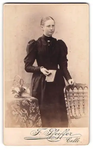 Fotografie F. Pfeiffer, Celle, Westcellerthorstr. 15, Junge Dame im schwarzen Kleid mit Brosche und Buch