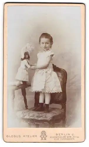 Fotografie Globus Atelier, Berlin, junges Mädchen mit grosser Puppe auf einem Stuhl stehend