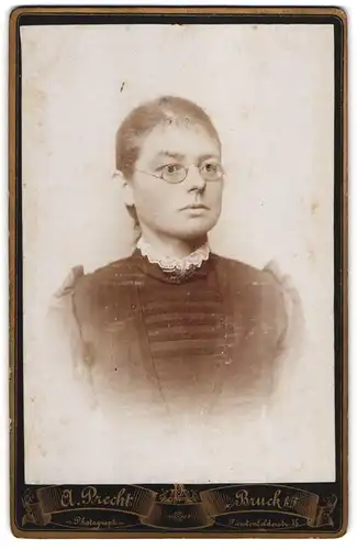 Fotografie A. Precht, Bruck b. F., Fürstenfelderstr. 35, Junge Dame in schwarzem Kleid mit weissem Kragen und Brille