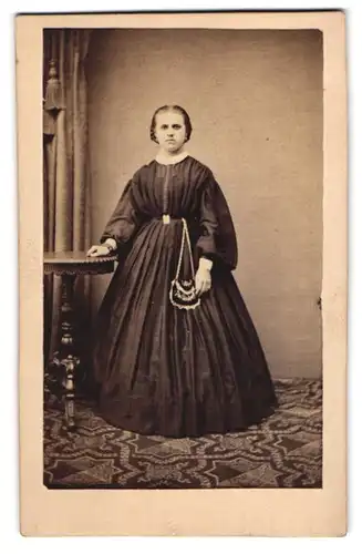 Fotografie Gebrüder Träger, Coethen, junge Frau im schwarzen Kleid mit verzierter Handtasche