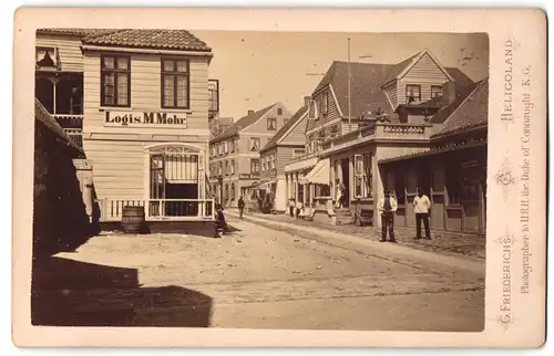 Fotografie G. Friederichs, Heligoland, Ansicht Helgoland, Hindmachstrasse 2 mit Logis M. Mohr, Geschäfte und Passanten