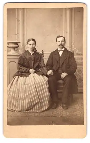 Fotografie H. Fischer, Halle / Saale, Ehepaar im dunklen Anzug und im gestreiften Rock mit dunkler Bluse