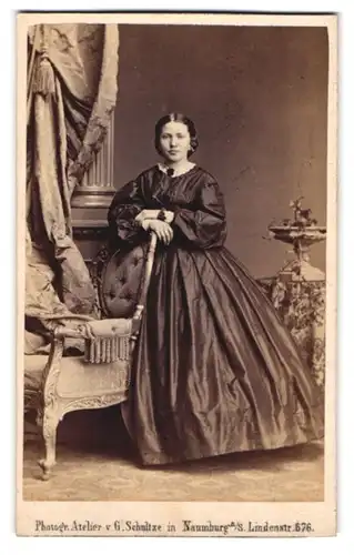 Fotografie G. Schultze, Naumburg / Saale, junge Frau im Biedermeierkleid stehend am Stuhl