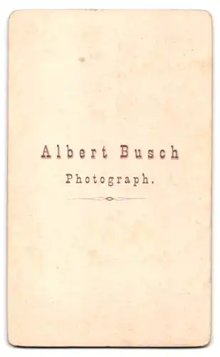 Fotografie Albert Busch, Ort unbekannt, niedliches Kleinkind im Kleid sitzt auf einem Hocker