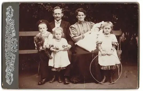 Fotografie unbekannter Fotograf und Ort, Eltern mit ihren vier Kindern, das kleinste noch im Wickel, Spielzeug