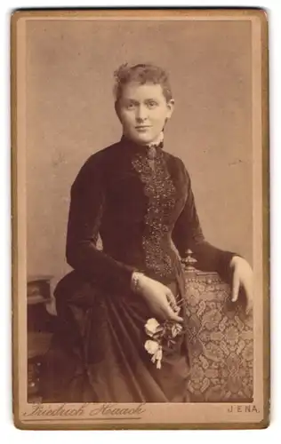 Fotografie Friedrich Haack, Jena, Junge Frau im taillierten schwarzen Kleid mit weissen Rosen