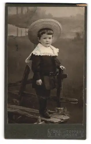 Fotografie Ferd. Steffen, Erlangen, Niedliche Junge im schwarzen Kleid mit grossem Hut und weissem Kragen
