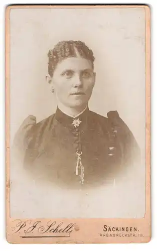 Fotografie P. J. Schell, Säckingen, Rheinbrückstr. 19, Hübsche Junge Dame mit Blumenbrosche und starrem Blick