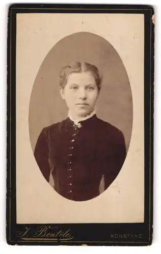 Fotografie J. Bentele, Konstanz, Junge Dame in tailliertem schwarzen Kleid mit weissem Kragen und Hochsteckfrisur