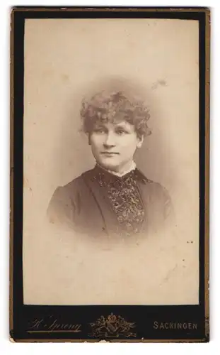 Fotografie R. Spreng, Säckingen, Hübsche junge Dame mit gelockten Haaren und schwarzem Kleid mit weissem Kragen