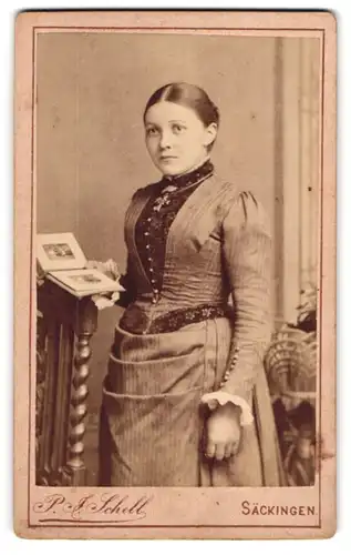 Fotografie P. J. Schell, Säckingen, Rheinbrückstr. 19, Schöne junge Frau mit Kreuzkette und Photobuch im Kleid