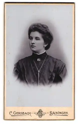 Fotografie C. Gersbach, Säckingen, Junge Dame mit breiter Hochsteckfrisur im schwarzen Kleid und langer Silberkette
