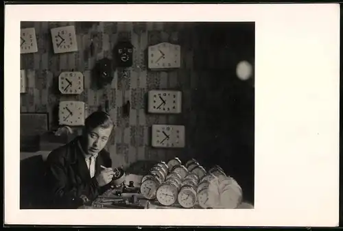 Fotografie Uhrmacher bei der Arbeit in seiner Werkstatt zwischen zahlreichen Uhren