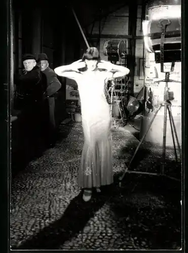 Fotografie Filmaufnahmen, Schauspielerin im Scheinwerferlicht neben einer Litfasssäule im Studio