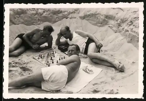 Fotografie Schach - Chess, Männer am Strand neben Schachbrett liegend