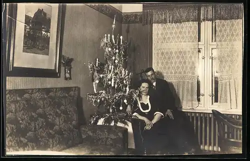 Fotografie Weihnachten, Paar neben Weihnachtsbaum in der Stube