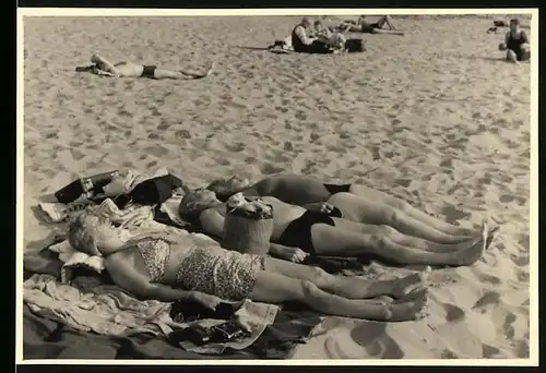 Fotografie Bademode, Sonnenanbeter im Bikini & Badehose am Strand liegend