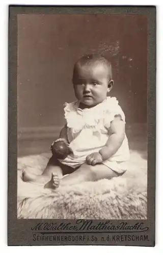 Fotografie M. Walther, Seifhennersdorf i. Sa., Baby mit Ball auf einem Fell