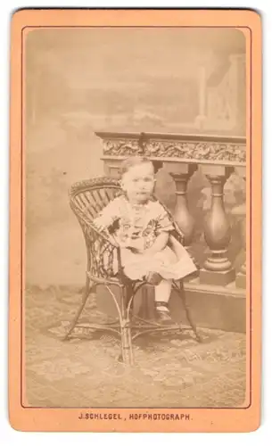Fotografie J. Schlegel, Reichenberg, Karlsstrasse 34, Kindchen im Kleidchen in einem Korbstuhl