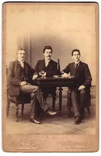 Fotografie Wilh. Gräf, Quakenbrück, drei Herren beim Umtrunk mit Rotwein im Atelier