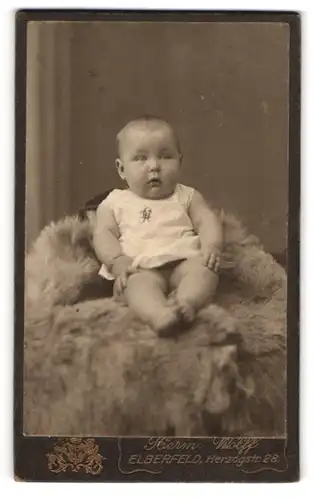 Fotografie Hermann Wolff, Elberfeld, Herzogstrasse 28, Baby im Strampler auf einem Fell