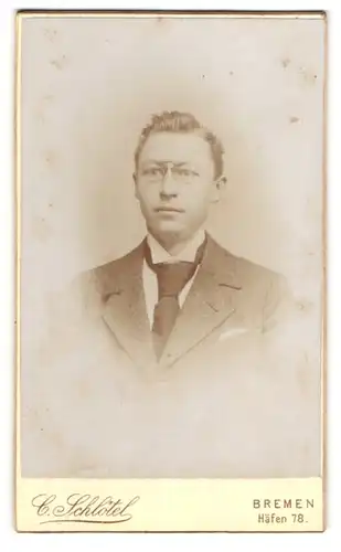 Fotografie C. Schlötel, Bremen, Häfen 78, Junger Mann im grauen Anzug mit breiter Krawatte und Zwicker