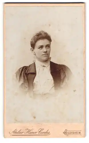 Fotografie Heinr. Cordes, Hildesheim, Zingel 36, Hübsche Dame in weisser Bluse mit Brosche und Locken