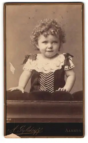 Fotografie A. Gylstorff, Aarhus, niedliches kleines Mädchen mit Locken und Schleifen am Kleid