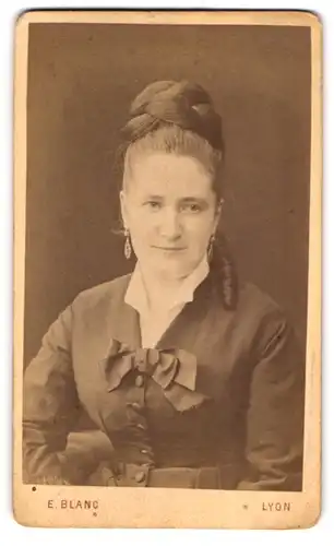 Fotografie E. Blanc, Lyon, Dame im dunklen Kleid mit hochgesteckten Haaren und Ohrringen