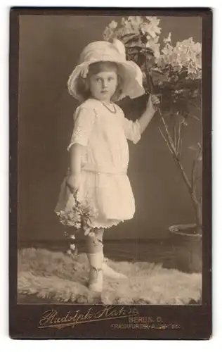 Fotografie Rudolph Hahn, Berlin, Portrait niedliches kleines Mädchen im weissen Kleid mit grossen Hut