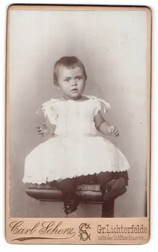 Fotografie Carl Scherz, Gr. Lichterfelde, Portrait niedliches Kleinkind im weissen Kleidchen