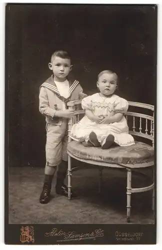 Fotografie Samson & Co., Düsseldorf, Portrait kleiner Junge im Matrosenanzug und sitzendes kleines Mädchen
