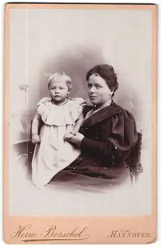 Fotografie Herm. Borschel, Hannover, Portrait sitzende Dame im schwarzen Kleid mit kleinem Mädchen im Arm