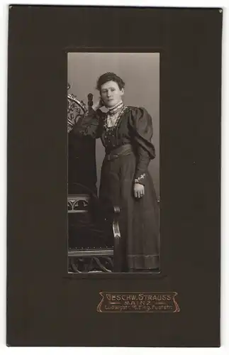 Fotografie Geschw. Strauss, Mainz, Portrait junge Dame im hübschen Kleid an Stuhl glehnt