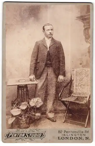 Fotografie W. Goebelhoff, London-N, Portrait modisch gekleideter Herr an Tisch gelehnt