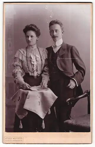 Fotografie Atelier Wertheim, Berlin, Portrait junges Paar in hübscher Kleidung mit Zeitung am Tisch