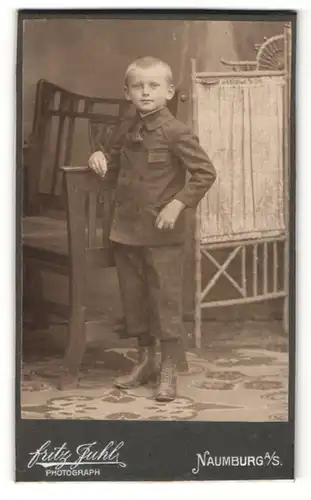Fotografie Fritz Juhl, Naumburg a / S., Portrait hübsch gekleideter Junge an Stuhl gelehnt