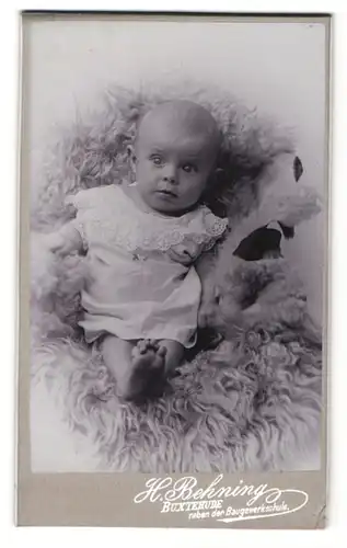 Fotografie H. Behning, Buxtehude, Kind in Kleid auf Fell