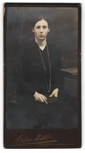 Fotografie Atelier Mehler, Bielefeld, Portrait sitzende Dame in schwarzer Kleidung mit Buch in der Hand