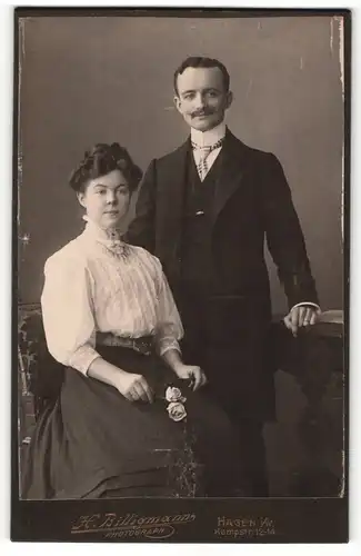 Fotografie H. Billigmann, Hagen i / W., Portrait hübsches Paar in zeitgenössischer Kleidung am Tisch