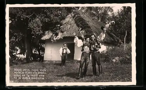 AK Fröhliche Männer in tschechischer Tracht vor einer strohgedeckten Hütte