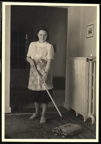 Fotografie Hausfrau mit Teppichkehrer bei der Hausarbeit