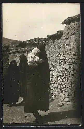 Foto-AK Mazedonien, Vollverschleierte Frauen mit Kind vor einer Mauer, Strassenszene