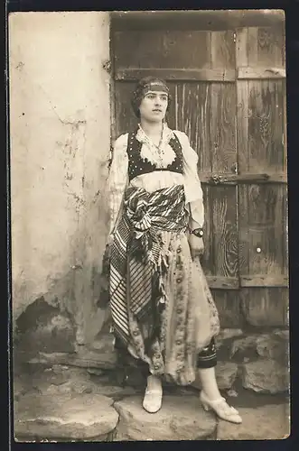 Foto-AK Veles, Junge Frau in Tracht vor einem Holztor
