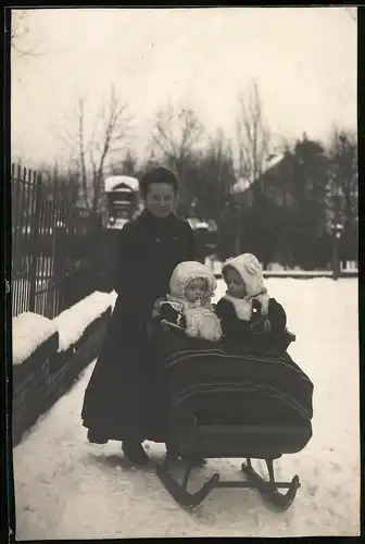 Fotografie Mutter mit Kinderwagen auf Kufen, niedliche Kinder tragen modische Winterkleidung